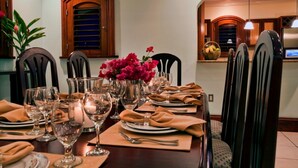 A dining table set with multiple wine glasses, plates, and a centerpiece of pink flowers.