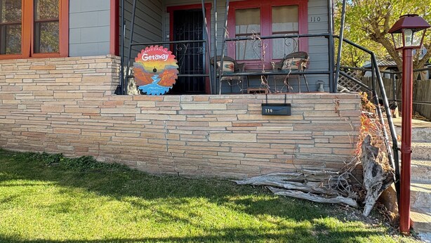 A two-story house with a stone facade, a red roof, and a porch with a swing set. - Grand Canyon & Route 66: Historic Williams Getaway (Williams)