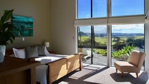 A bedroom with a large window, a bed, a chair, and a plant. - Cliffhouse, Taiharuru, Northland (Whangarei Heads)
