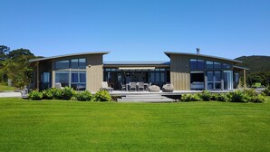A modern two-story house with large glass windows, a flat roof, and a well-maintained lawn. - Cliffhouse, Taiharuru, Northland (Whangarei Heads)