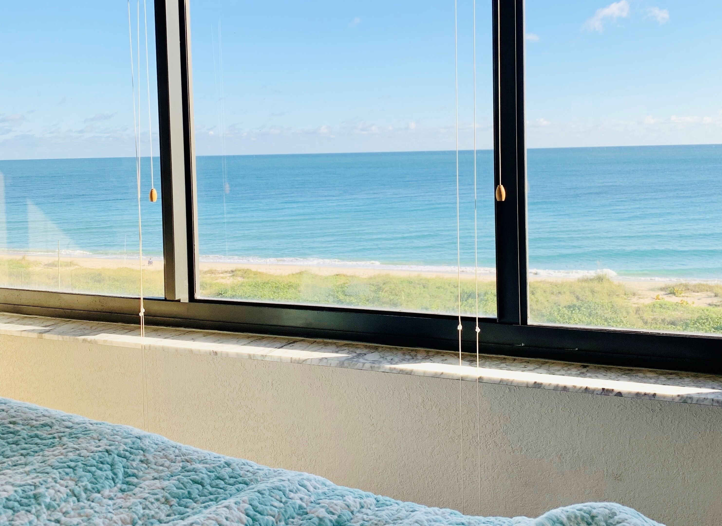A room with a large window overlooking a beach.