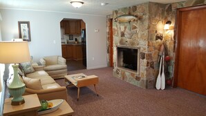 Ein Wohnzimmer mit Kamin aus Stein, einer Couch, einem Couchtisch und einem Fernseher.