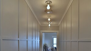 Un couloir étroit doté d’un plancher en bois et de murs recouverts de panneaux blancs.