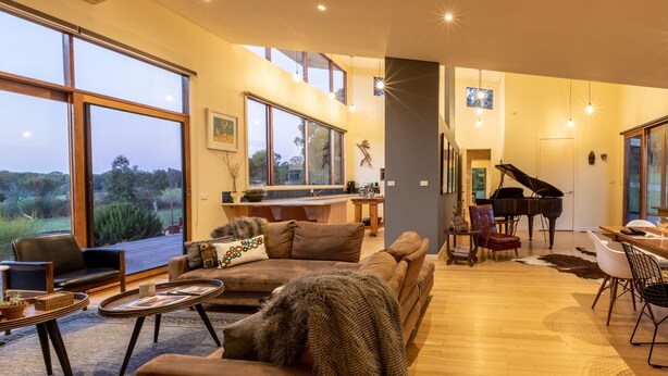 Amplio salón con piano, ventanas grandes y un rincón de estar acogedor.