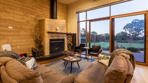 Una sala de estar acogedora con chimenea, asientos cómodos y un ventanal con vistas al exterior.