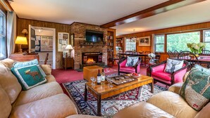 A cozy living room with leather sofas, a fireplace, a television, and a dining area with wooden furniture. - Perfect Reunion House for 18! 8 bedrooms, 5 baths, Pool, Tennis, Big lawn, Dogs! (Manchester)