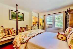 Une chambre à coucher avec un lit à baldaquin, une table de chevet, une commode, une fenêtre avec des rideaux et un tableau représentant un paysage, encadré, accroché au mur.