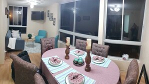 Un coin repas avec une table dressée pour quatre personnes, entourée de quatre chaises rembourrées.