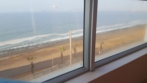 Une vue d’une plage bordée de palmiers, avec une route qui longe le rivage.