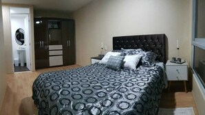 Une chambre à coucher avec un grand lit, une armoire, une table de chevet et une fenêtre.
