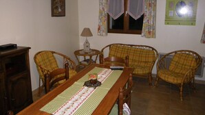 A dining area with a wooden table, four chairs, a lamp, and a window with curtains.