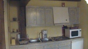 A kitchen with white cabinets, a sink, a stove, a microwave, and a coffee maker.
