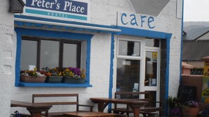 Peter's Place Hostel with a cafe, wooden benches outside, and flower pots on the windowsill. - Cosy cottage near village  beach  Links and Hogs Head Golf Courses (Waterville)