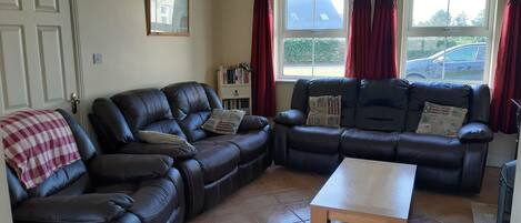 A living room with a sectional sofa, a wooden coffee table, and a bookshelf.
