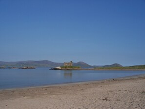 A sandy beach with a small stone structure in the water.