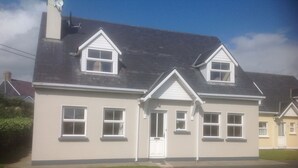 A two-story house with a gabled roof, a front door, and multiple windows. - Cosy cottage near village  beach  Links and Hogs Head Golf Courses (Waterville)