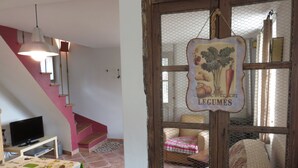 A dining area with a table set for two, a television, and a staircase leading to an upper level.