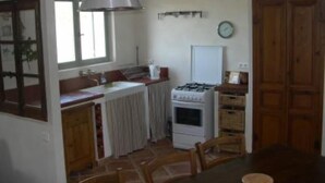 A kitchen with a gas stove, a white refrigerator, wooden cabinets, and a dining table with chairs.