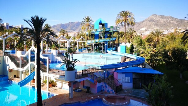 A resort with a large swimming pool, a water slide, and a view of mountains. - Beautiful apartment on the beach. A Luxury. (Benalmádena)