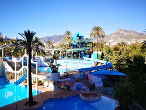 Een resort met een groot zwembad, een glijbaan en uitzicht op bergen.
