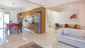 A spacious living area with a dining table, kitchen with appliances, and a sofa. - Charming Waterfront Villa in South Rhodes , near Monolithos and Prasonissi (Apolakkia)