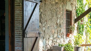 Un muro de piedra rústica con una puerta de madera y una pequeña mesa con sillas.