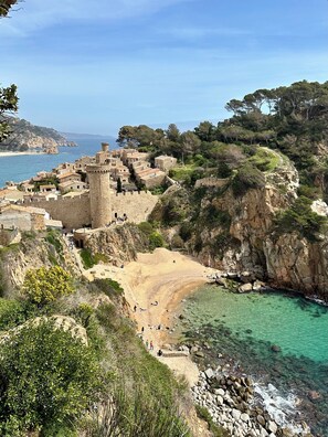 A coastal village with stone buildings, a beach, and a clear view of the sea.