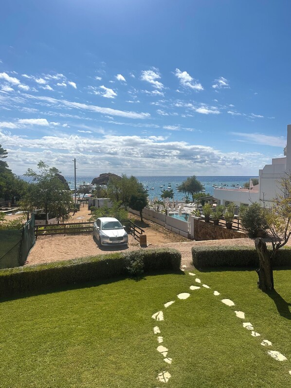 A residential area with a swimming pool, a parked car, and a clear view of the sea.
