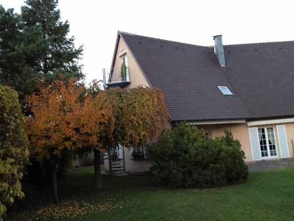 Situated in a suburban area, this single-story home features a sloped roof and a chimney, surrounded by a well-maintained lawn and trees.