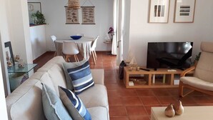 Ein Wohnzimmer mit Sofa, Fernseher und Essbereich.