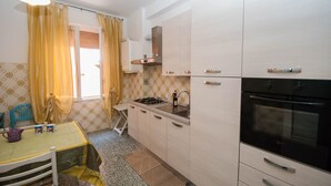 Une cuisine compacte équipée d’une cuisinière à gaz, d’un four et d’un petit coin repas avec une table et des chaises.