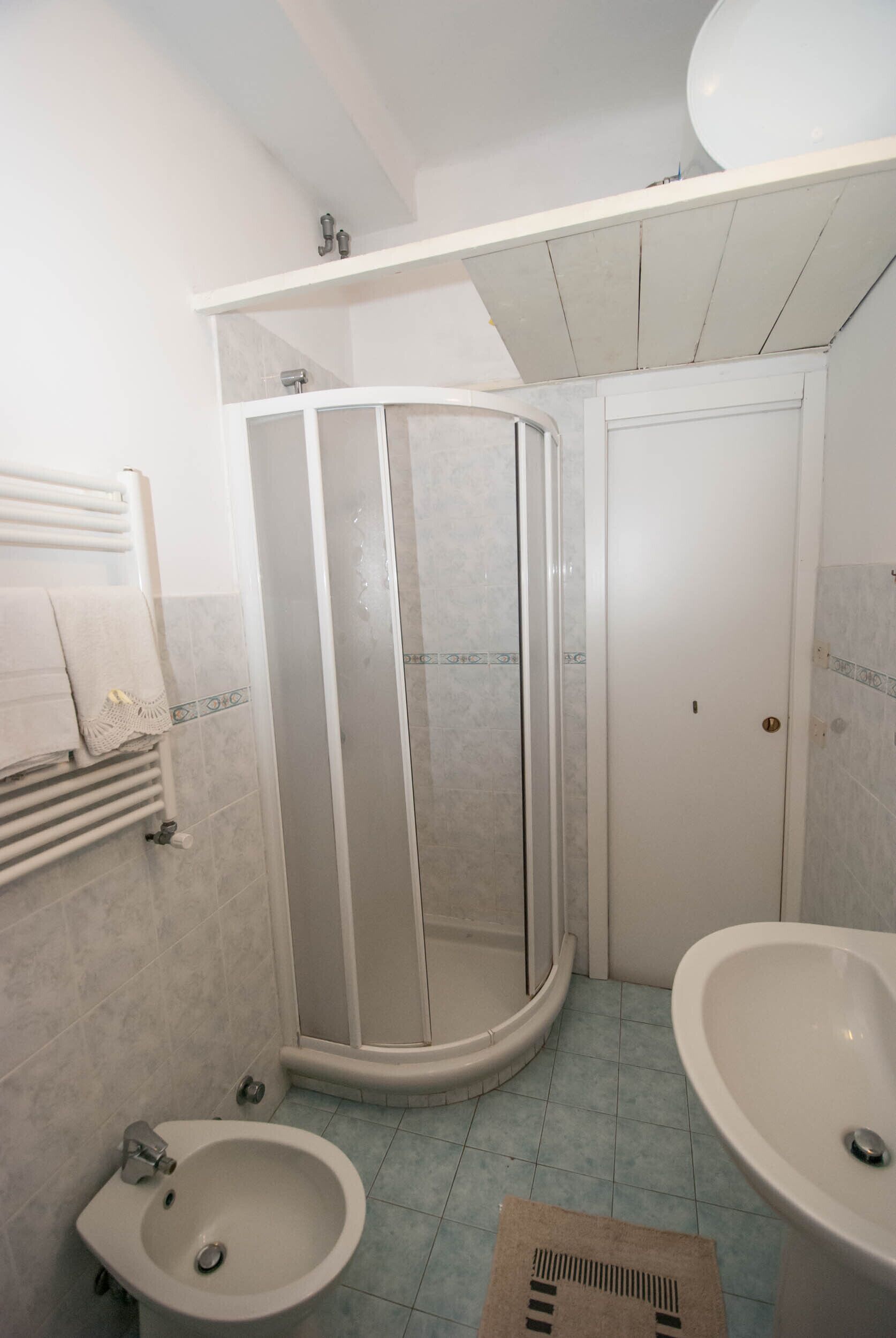 Ein Badezimmer mit Duschkabine, Bidet und Waschbecken.