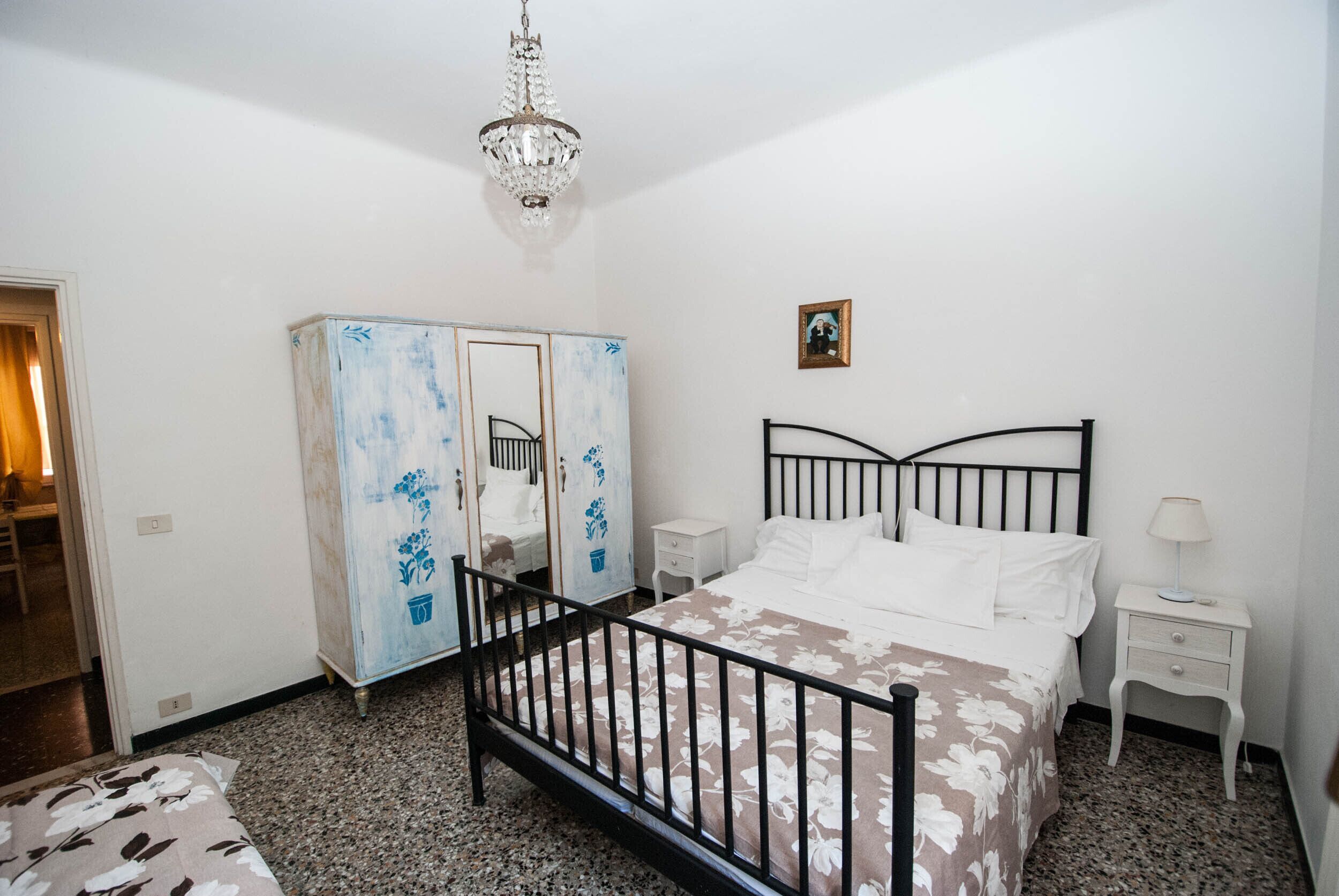 Een slaapkamer met een bed, nachtkastje, kast en een kroonluchter.