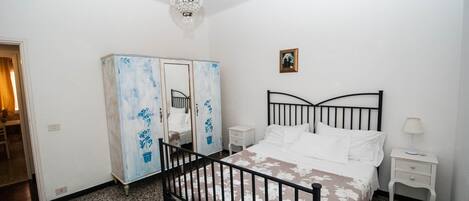 Een slaapkamer met een bed, nachtkastje, kast en een kroonluchter.
