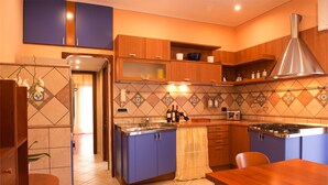 A modern kitchen with blue cabinets, a central island, and a stainless steel range hood. - Casa Chicco - My Rental Homes (Sorrento)