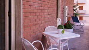 A patio with a white table and chairs, a potted plant, and a blue chair. - Casa Chicco - My Rental Homes (Sorrento)