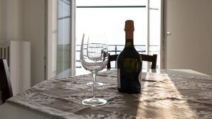 Een tafel met een champagnefles en een leeg glas, op een kantkleed.