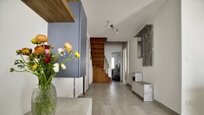 Een moderne gang met een houten trap, een bloevas en een minimalistisch design.