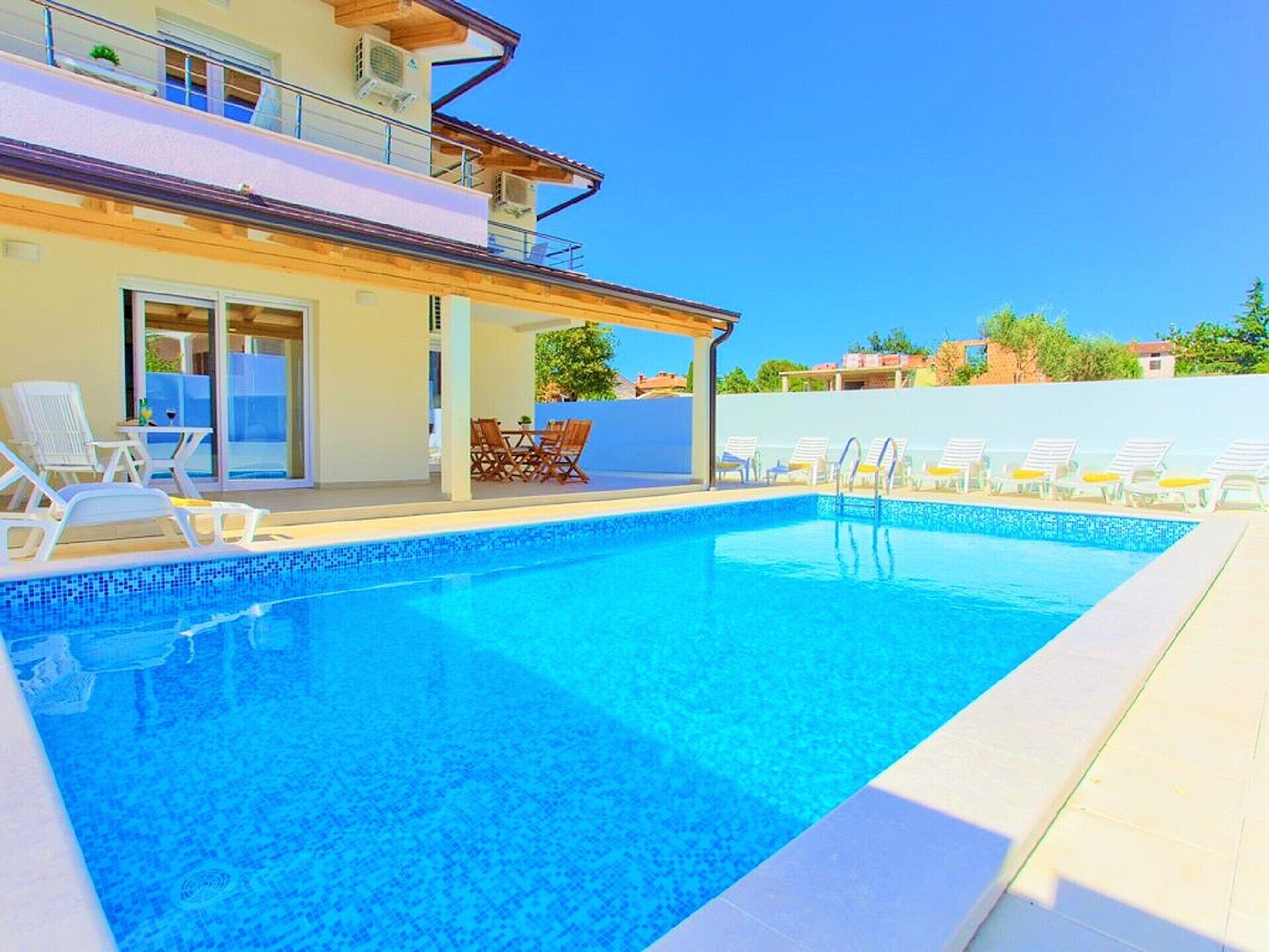 A swimming pool with lounge chairs and a covered seating area.