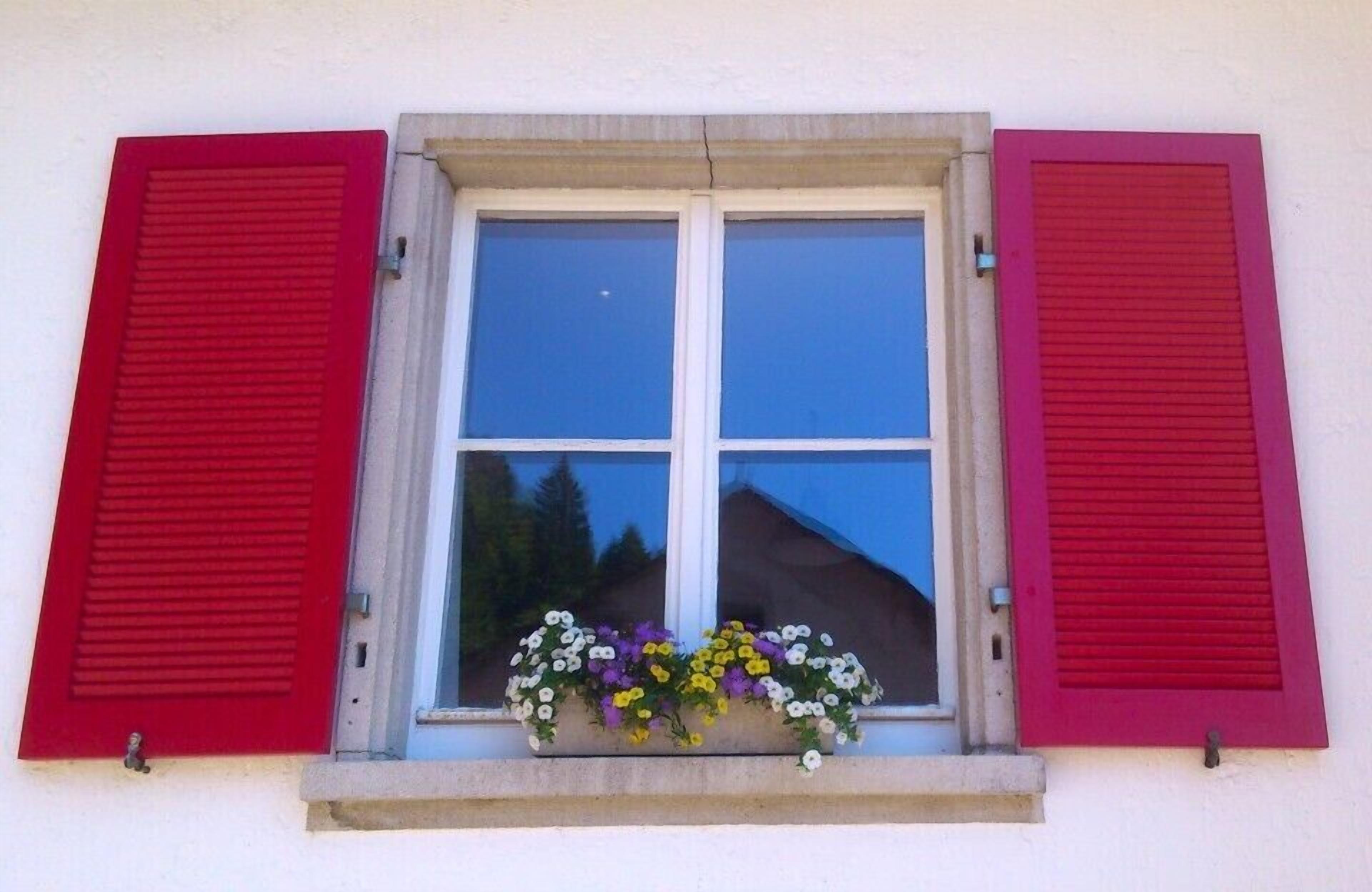 Une fenêtre avec des volets rouges et une jardinière en dessous.