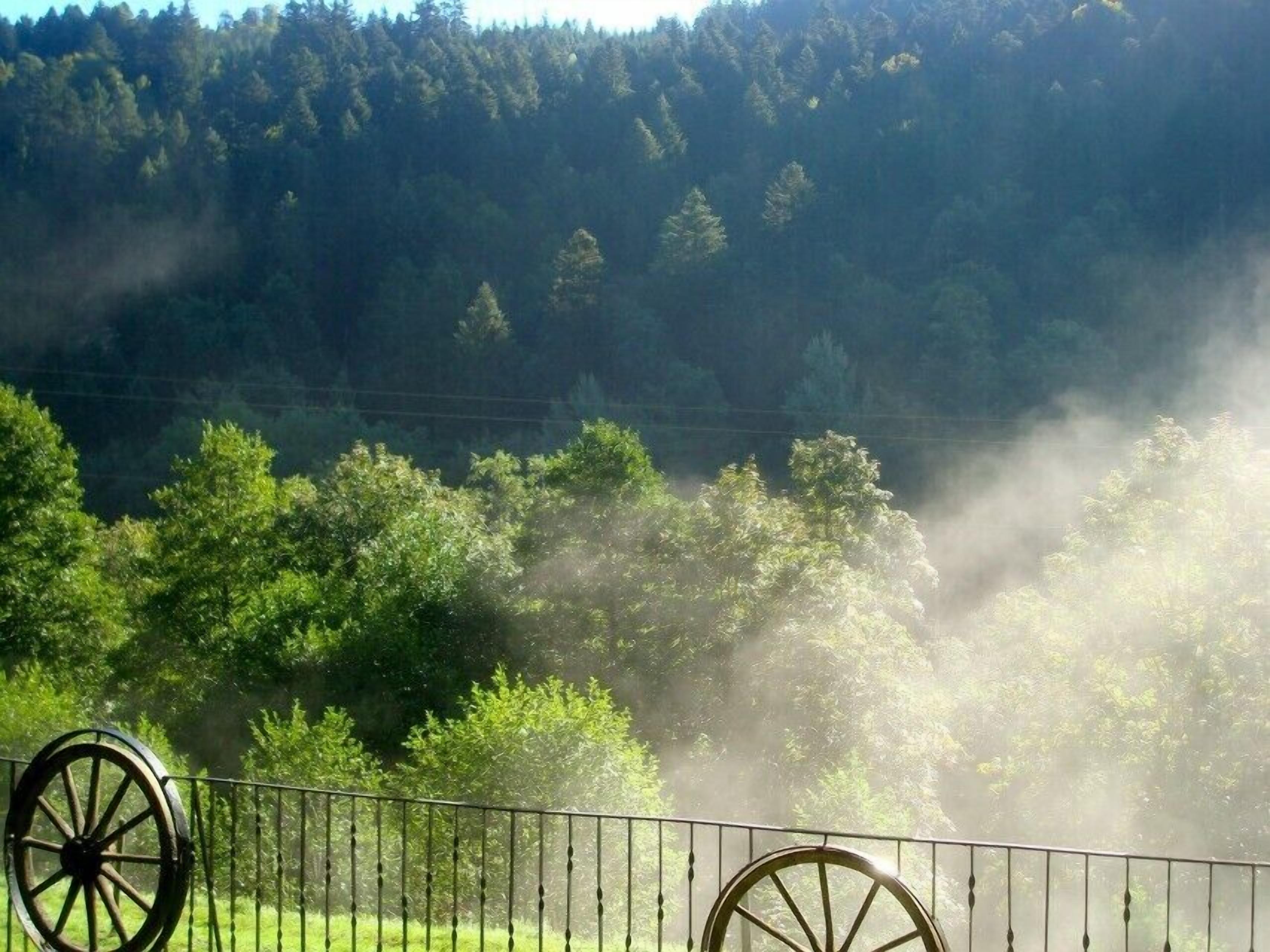 A rural landscape with a fence and two large wheels, likely part of a historical site or monument.