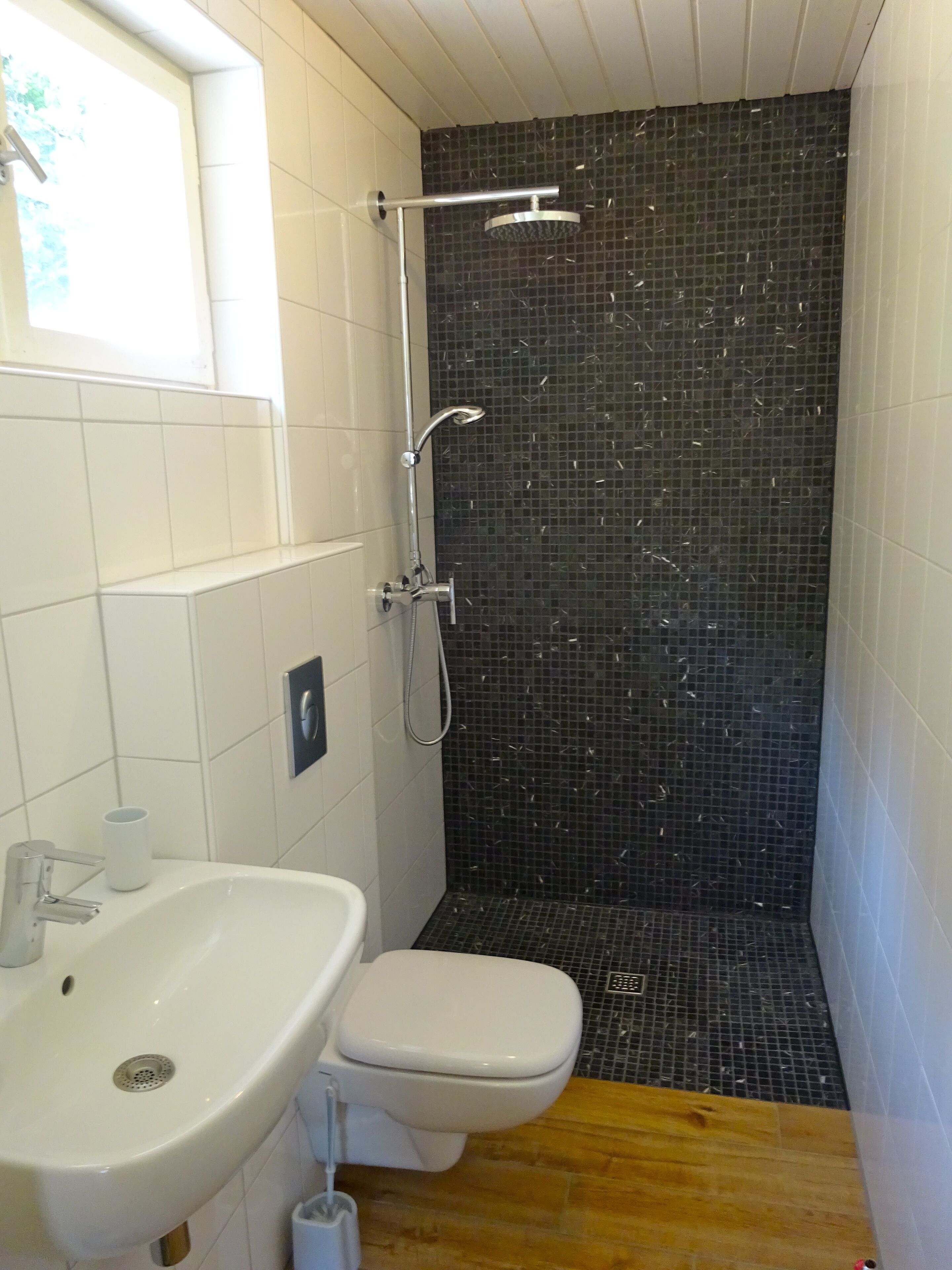 A bathroom with a white sink, toilet, and shower.