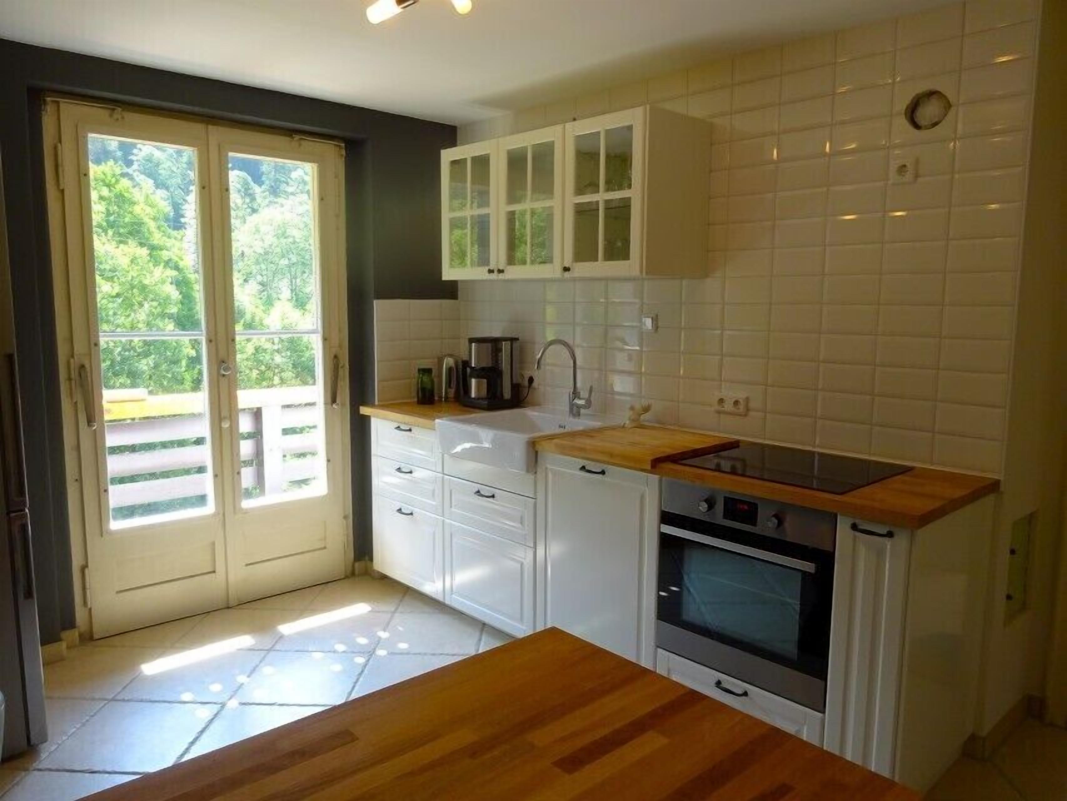A compact kitchen with white cabinets, a wooden countertop, and a built-in oven.