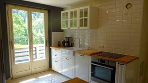 Una cocina compacta con armarios blancos, encimera de madera y horno integrado.