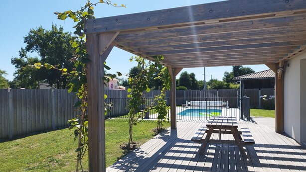En träaltan med en pergola, en pool och ett picknickbord.