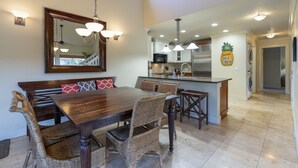 Un comedor con una mesa de madera y sillas de mimbre, una cocina con electrodomésticos modernos y un espejo grande sobre la mesa.