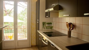A kitchen with a built-in oven, a stovetop, and a window with a view of greenery outside.