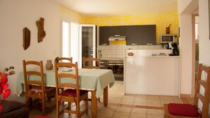 A compact kitchen with a dining area, featuring a microwave, stove, and a small island.