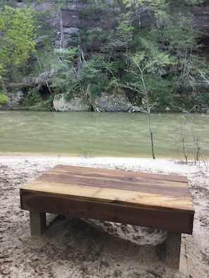 A wooden bench by a river with a rocky cliff and greenery in the background. - Looking for a remote location? Forests, Creeks, and Sipsey! And new WiFi!  (Double Springs)