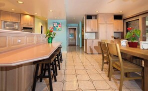 A kitchen with a central island, wooden cabinets, and a dining area with chairs.